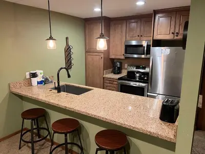 a kitchen with a sink and a counter with stools at Horizons Condo with Communal Clubhouse in Mammoth Lakes