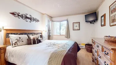 a bedroom with a large bed and a television at Summit Cozy Condo Getaway in Mammoth Lakes
