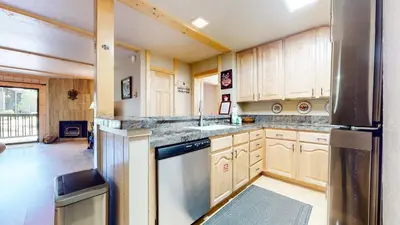 a kitchen with wooden cabinets and a stainless steel refrigerator at Summit Cozy Condo Getaway in Mammoth Lakes