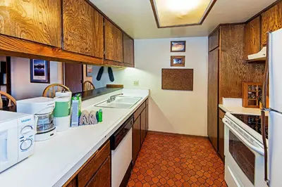 a kitchen with wooden cabinets and a white sink at Horizons 4 - Pool & Hot Tub Access in Mammoth Lakes