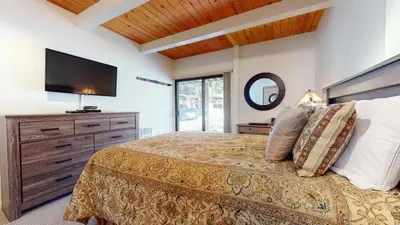 a bedroom with a large bed with a flat screen tv at Villa De Los Pinos Year-Round Activities Nearby Shopping & Restaurants in Mammoth Lakes