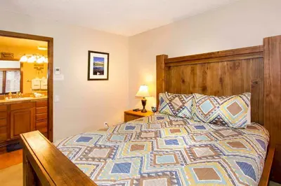 a bedroom with a bed with a wooden headboard and a sink at Winterset #28 Shared Hot Tub & Sauna in Mammoth Lakes