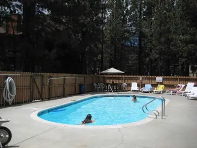 two people are swimming in a swimming pool at Cozy Condo for 4 Near Shuttle & Eagle Lodge in Mammoth Lakes