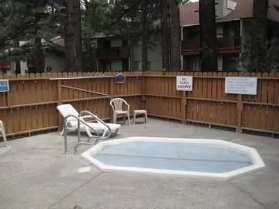 a swimming pool with chairs and a fence at Cozy Condo for 4 Near Shuttle & Eagle Lodge in Mammoth Lakes