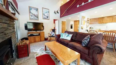 a living room with a brown couch and a tv at La Residence - Shared Pool Hot Tub & More in Mammoth Lakes
