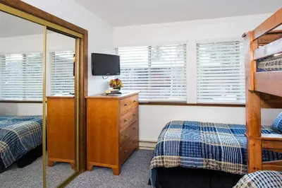 a bedroom with two beds and a dresser with a television at Mammoth Estates - 4 Seasons of Beauty with Accessible Amenities in Mammoth Lakes