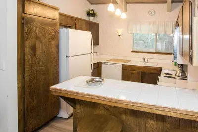 a kitchen with a white refrigerator and wooden cabinets at Mammoth Estates - 4 Seasons of Beauty with Accessible Amenities in Mammoth Lakes