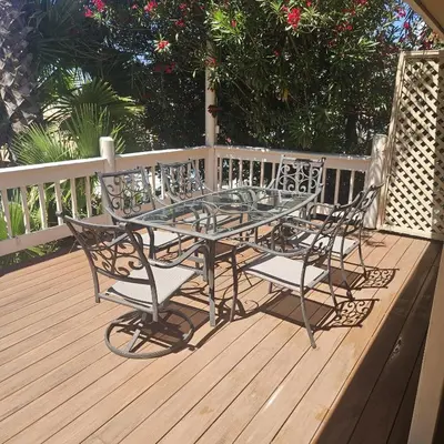 a glass table and chairs on a wooden deck at Waterfront Elegance in Discovery Bay