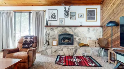 a living room with a stone fireplace and a chair at Mammoth Hygge - Centrally Located in Mammoth Lakes