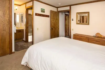a bedroom with a white bed and a bathroom at Mammoth Point #129 - Balcony with Mountain Views in Mammoth Lakes