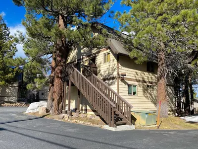 a house with a wooden staircase next to a tree at Mammoth View Villas - Near Hike & Bike Trails in Mammoth Lakes