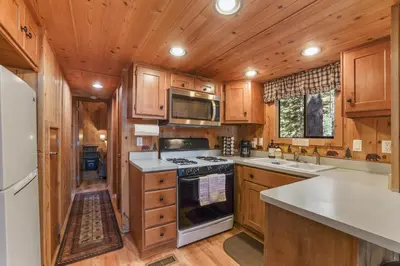 a kitchen with wooden cabinets and a stove top oven at The Cozy Cub Cabin 7 Min to Lake in South Lake Tahoe