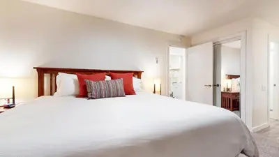 a bedroom with a large white bed with red pillows at Mid Century Modern Cabin #212 - Walk to Village in Mammoth Lakes