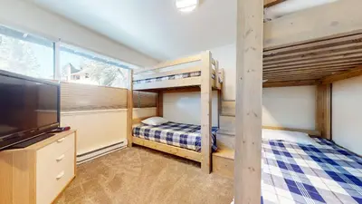 a bedroom with two bunk beds and a flat screen tv at Mid Century Modern Cabin #212 - Walk to Village in Mammoth Lakes