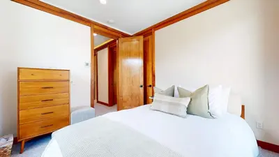 a bedroom with a white bed and a wooden dresser at Obsidian Dreaming - On the Sierra Star Golf Course in Mammoth Lakes