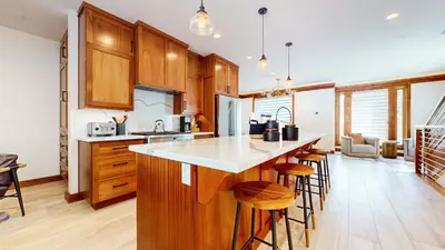 a kitchen with wooden cabinets and a kitchen island with bar stools at Obsidian Ski & Golf Villa - 3 BDR Prime Location in Mammoth Lakes