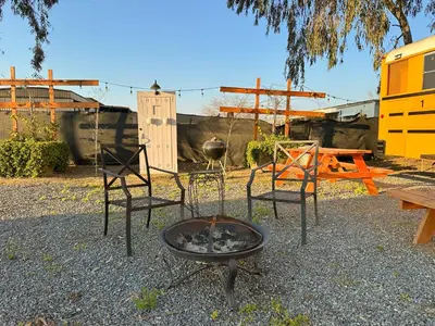 two chairs and a fire pit in a yard at The Magic Skoolie in Visalia