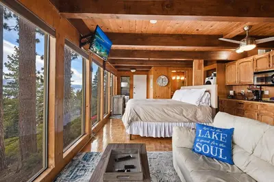 a bedroom with a bed and a couch in a room with windows at Stunning Views at Stargazer - Lakefront Studio in Crystal Bay