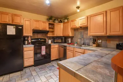 a kitchen with wooden cabinets and a black refrigerator at Tahoe Pines Cabin in Homewood