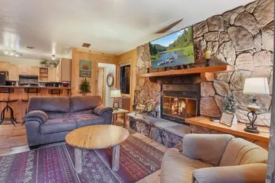 a living room with a stone wall with a fireplace at Tahoe Pines Cabin in Homewood