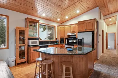 a kitchen with wooden cabinets and a island with bar stools at Truckee Pines Retreat - Game Room & Forest Views in Truckee