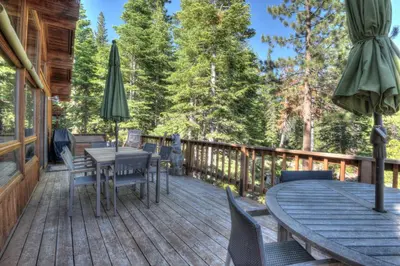 a wooden deck with a table and chairs and an umbrella at Vista Point - 5 Minutes to Kings Beach in Tahoe Vista