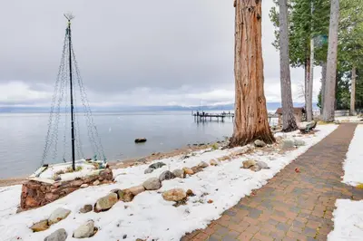 a walkway next to the water with a tree at Waters Edge Escape - Patio with BBQ Near Beach in Tahoma
