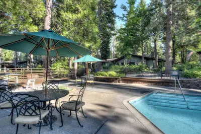 a table with an umbrella and chairs next to a pool at Waters Edge Oasis - Shared Pool & Pier Access in Tahoma