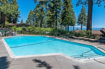 a large swimming pool in a yard with trees at Waters Edge Vista - HOA Pool & Pier Access in Tahoma