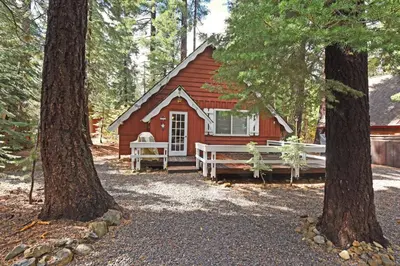 a red cabin in the woods with two trees at Woodland Chalet - 2 miles from Beach Access in Tahoma