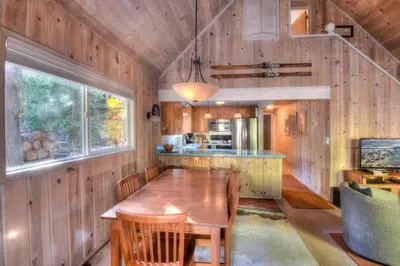 a dining room with a wooden table and a kitchen at Woodland Chalet - 2 miles from Beach Access in Tahoma