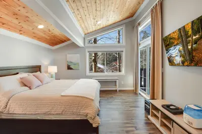 a bedroom with a large bed and two windows at Alpine Chalet Nature Lovers Rejoice Chic 4 BDR in Alpine Meadows