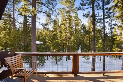 a wooden chair sitting on a deck with trees at Woodside Hideout - Hop Away from Activities in Tahoma