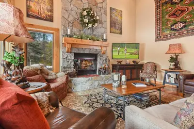 a living room with a stone fireplace with a tv at Wulf's Lodge at Olympic Valley - Unwind in Hot Tub in Olympic Valley