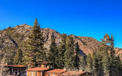 a mountain with a house and trees in front of it at Alpine Meadows Peak 15 Min to Commons Beach in Alpine Meadows