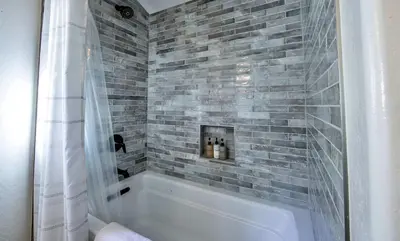 a bathroom with a white tub and a gray brick wall at Bearfoot Lodge Near Fishing and Hiking in Truckee