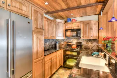 a kitchen with wooden cabinets and a stainless steel refrigerator at Brockway Springs Lodge Steps to Lake Access in Kings Beach