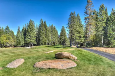 a golf course with rocks on the grass and a road at Cedar Chateau with Game Room & HOA Access in Truckee