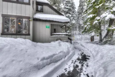 a house covered in snow next to a driveway at Granlibakken Retreat Near Tahoe Beach in Tahoe City