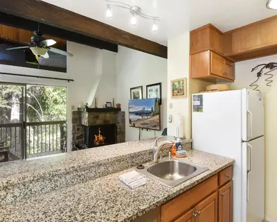 a kitchen with a sink and a refrigerator and a fireplace at Enjoy Forest Views Retreat at Kingswood Village in Kings Beach
