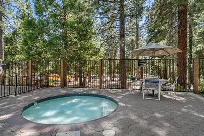 a swimming pool with an umbrella and a table and a chair at Enjoy Forest Views Retreat at Kingswood Village in Kings Beach