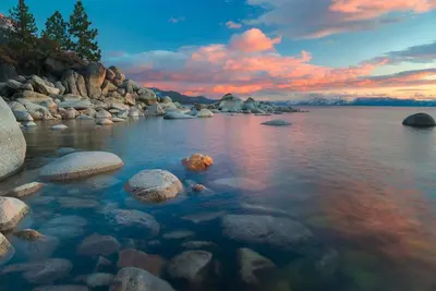 a rocky shore with rocks in the water at sunset at Crystal Shores Villa Lake Views & Hiking in Incline Village