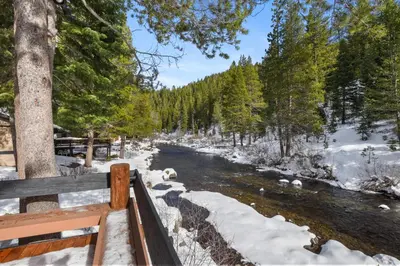 a river covered in snow next to a wooden fence at Joy on the River Stunning Waterfront Home for 10 in Olympic Valley