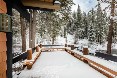 a snow covered porch of a cabin with trees at Joy on the River Stunning Waterfront Home for 10 in Olympic Valley