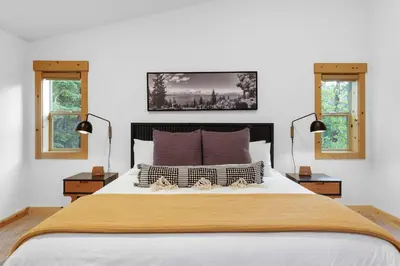 a bedroom with a large bed with two windows at Modern Lake Tahoe Retreat Ski and Swim in Tahoe Vista