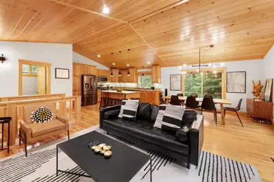 a living room with a black couch and a kitchen at Modern Lake Tahoe Retreat Ski and Swim in Tahoe Vista