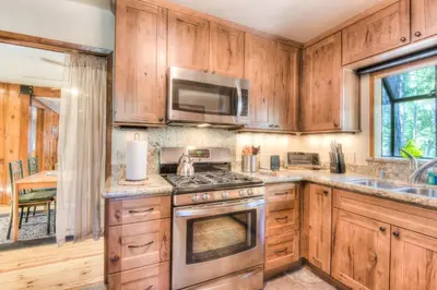 a kitchen with wooden cabinets and a stove top oven at Moonlight Cove w Grill Tahoe Beach Next Door in Tahoe Vista