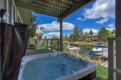 a hot tub on a patio with a view of a river at Lucerne Lake House - Ski Lease 30plus Days in South Lake Tahoe
