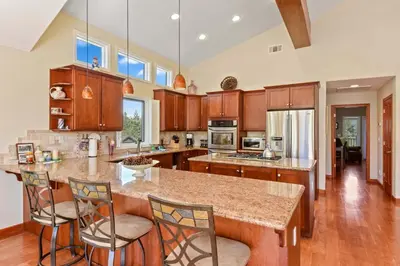 a kitchen with wooden cabinets and a island with bar stools at Mule Meadows - Classy Split level South Tahoe home in South Lake Tahoe