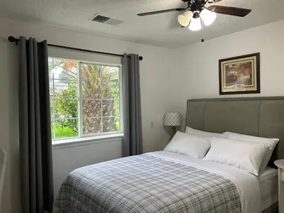 a bedroom with a bed with a ceiling fan and a window at Private Suites in Sacramento